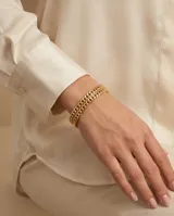 Pulsera esclava de acero con baño de oro, diseño de cadena de eslabones entrelazados con acabado brillante.