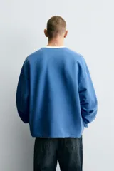 Camiseta de manga larga con cuello redondo y ajuste relajado. Presenta un efecto lavado, acabados en rib en cuello y puños, y un estampado frontal con el número 95 en contraste.