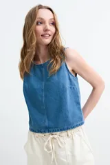 Top de denim sin mangas, color crudo, con cuello redondo y costura central visible.