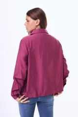 Camisa negra de corte clásico con cuello camisero y detalle de lazo ajustable en el cuello. Presenta cierre frontal con botones y mangas largas con puños abotonados.