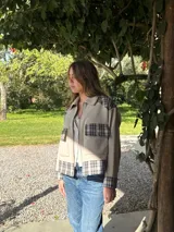 Campera de lana con diseño combinado en color beige liso y paneles a cuadros en tonos grises. Presenta cuello camisero, cierre frontal, bolsillos con solapa en el pecho y puños con detalle a cuadros.
