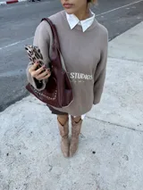 Bolso tipo tote de cuero color visón con apliques de tachas plateadas. Tiene doble asa corta, cierre con imán y bolsillo externo con imán. Incluye un sobre interno grande con gancho.