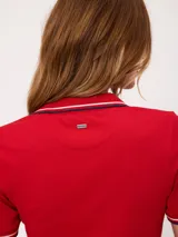 Remera polo azul marino de manga corta, con cuello en V sin botones y ribetes tricolores en el cuello y los puños.