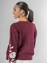 Sweater de tejido de punto color borgoña con escote en V y bordado de flores blancas en las mangas.