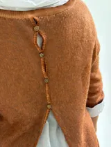 Sweater de punto color naranja con diseño asimétrico, que incluye una bufanda a juego con detalles bordados y una camisa blanca de base integrada.