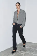 Camisa de corte fluido confeccionada en mezcla de viscosa, con diseño de rayas verticales en blanco y negro. Presenta cuello solapa, manga larga con puños, bolsillo de plastrón en el pecho, bajo redondeado y cierre frontal con botones.