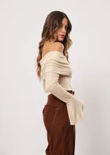 Blusa beige con hombros descubiertos, mangas largas acampanadas y confeccionada en tela stretch con lurex.