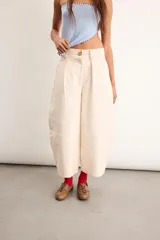 Pantalón de gabardina de algodón color marfil, de silueta tipo barrel con pinzas delanteras, tiro alto y diseño holgado con costuras decorativas.