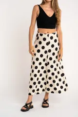 Falda midi color crudo con estampado de lunares negros, corte evasé y cintura alta.