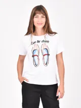 Remera blanca de manga corta con cuello redondo y un estampado frontal de un jarrón azul a rayas con flores rosadas.