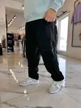 Pantalón cargo de jean azul claro, con bolsillos laterales tipo cargo en las piernas y bolsillos frontales aplicados, de corte ancho y holgado.