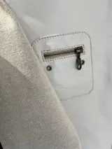 Chaqueta bicolor en tonos beige y tostado, con frente de cuero sintético y mangas y espalda de tejido de punto. Cuenta con cuello mao, cierre frontal y bolsillos frontales con cierre.