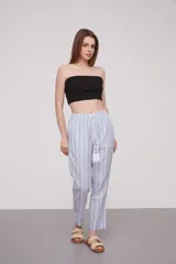 Pantalón babucha celeste con rayas verticales blancas, cintura elástica con cordón y detalle de borlas.