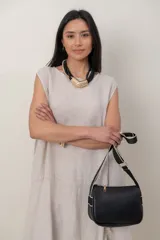 Vestido midi de lino color beige, sin mangas y con cuello redondo. Cuenta con un diseño irregular con detalle de volado vertical a un costado.