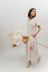 Vestido midi de popelina 100% algodón color beige, con estampado floral en tonos celestes y rosados, cuello camisero, manga corta, cierre frontal con botones y bolsillos laterales.