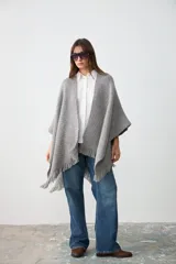Ruana de tejido artesanal en lana merino, lino y viscosa, con textura aireada y terminación de flecos en los bordes. Diseño versátil y envolvente, ideal para usar como abrigo ligero.