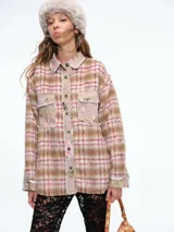 Camisa de corte oversize confeccionada en tejido de textura suave con estampado de cuadros y detalles de patchwork floral en los bolsillos delanteros, cuello y tapeta de botones. Presenta bordes deshilachados, cierre frontal con botones metálicos y dos bolsillos con solapa en el pecho.