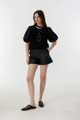 Top negro sin mangas de gamuza de cabra con apliques tribales de cuero de oveja al tono. Tiene cuello a la base y cierre metálico en la espalda.