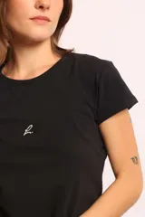 Remera básica gris melange, de calce cómodo, con cuello redondo, mangas cortas y un pequeño bordado minimalista en el frente.