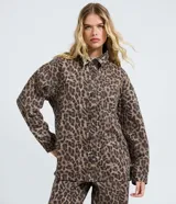 Camisa de corte oversized confeccionada en denim de algodón, con estampado animal print. Presenta cuello camisero, cierre frontal abotonado, manga larga y bolsillo en el pecho.