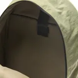 Mochila verde de tela con doble cierre, forro interior textil, compartimento para notebook pequeña y bolsillo externo con solapa.