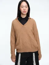 Sweater de tejido con textura peluda, cuello tipo polo y manga larga. Presenta un diseño de silueta cómoda y holgada.
