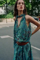Top sin mangas de cuello alto con lazo ajustable, escote en V y diseño cruzado en el delantero. Presenta un estampado paisley en tonos verdes, azules y rosados, con bajo elástico y forro interior.