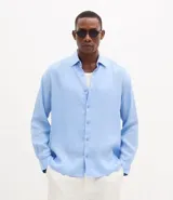 Camisa de corte relajado confeccionada en cambraia de lino puro. Presenta cuello inglés, cierre frontal con botones y mangas largas.