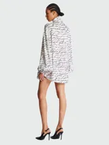 Camisa blanca con estampado de texto en negro, lazo en el cuello y mangas largas abullonadas.