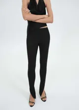 Leggings negros de corte entallado con aberturas en el bajo y detalle de puntilla en la cintura. Cuentan con cierre lateral invisible.
