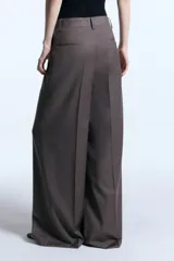 Pantalón sastrero de tiro alto con corte ancho y fluido, confeccionado en mezcla de lana. Presenta detalle de bordado en la cintura, cierre frontal y bolsillos laterales.
