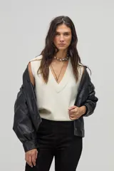 Chaleco tejido color crema con escote en V y terminaciones de rib.