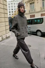 Pantalón de tiro alto confeccionado en material con efecto piel, con cintura elástica, bolsillos delanteros y nervio marcado en el frente. Presenta un diseño bombacho con bajo ajustable mediante cordones elásticos.