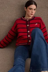 Cardigan de punto con diseño a rayas horizontales en azul marino y beige. Presenta cuello redondo, cierre frontal con botones grandes y mangas largas con puños acanalados en tono verde oliva. Incluye un pequeño bordado de una raqueta de tenis en el lateral.