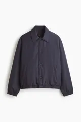 Campera de estilo coach, color azul marino, con cuello inglés, cierre frontal con botones a presión y bolsillos laterales insertados. Presenta puños y bajo con elástico, y cuenta con forro interior acolchado.
