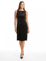Vestido midi sin mangas confeccionado en terciopelo negro. Presenta escote redondo cerrado en el frente y un profundo escote en V en la espalda. Su diseño sigue la línea del cuerpo con pinzas de entalle laterales y una falda que se abre ligeramente hacia el ruedo.