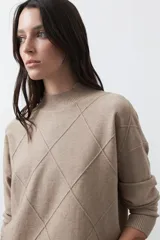 Polera de tejido de punto color gris oscuro, con cuello alto y diseño de rombos en relieve en el frente. Presenta un calce relajado con terminaciones en rib en cuello, puños y ruedo.