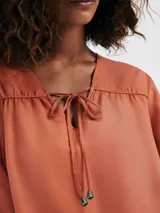 Blusa color marrón con escote en V y mangas largas.