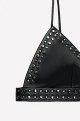 Bralette triangular negro de cuero con tirantes finos ajustables y tachas metálicas. Cierre trasero con ganchos metálicos. Colección especial Ludovic de Saint Sernin x ZARA.