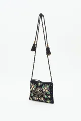 Cartera de mano o bandolera pequeña de terciopelo negro con bordado floral multicolor y apliques de lentejuelas y cuentas brillantes. Correa delgada negra con tachas doradas.