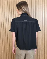 Camisa de manga corta color beige, con cuello alto con volados, botonadura frontal y mangas abullonadas con terminación fruncida.