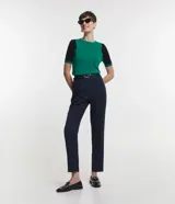 Blusa de viscosa con cuello redondo y mangas cortas. Presenta un diseño de bloques de color contrastantes, con cuerpo en tono malva y mangas en color negro, destacando por sus recortes asimétricos en la sisa.