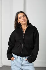 Campera de gamuza negra con cierre frontal, cuello camisero, bolsillos delanteros con solapa y puños con botón.