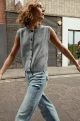 Chaleco de punto suave con cuello redondo, diseño sin mangas y cierre frontal con botones. Presenta terminaciones en rib en el cuello, sisas y ruedo.