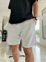 Bermuda de jogging gris melange con bolsillos laterales y sutil inscripción bordada en la pierna.
