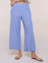 Pantalón crop de lino y rayón, con diseño wide leg de corte holgado, estampado tropical de hojas en tonos verde, azul y marrón sobre fondo blanco. Cuenta con pretina trasera elastizada y bolsillos delanteros.