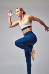 Top deportivo color beige con contorno inferior y tiras cruzadas en la espalda color borgoña. Cuenta con almohadillas removibles.