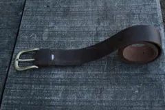 Cinturón marrón de cuero vacuno encerado con hebilla metálica dorada.