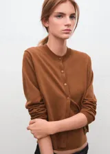 Cardigan de punto fino color tostado, con cuello redondo, manga larga y cierre frontal de botones.