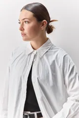 Camisa de algodón de calce relajado con cuello clásico, mangas largas con puños abotonados y cierre frontal con botones.